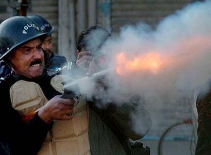 Un policía lanza una granada de gas lacrimógeno contra seguidores del PPP.
