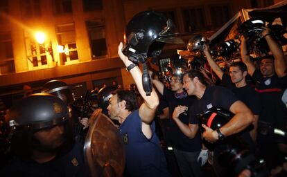 Los bomberos se quitan los cascos e invitan a los policías a hacer lo mismo.