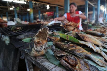 Un vendedor ofrece carne de 'lagarto' en un mercado cercano a la ciudad de Iquitos (Perú).