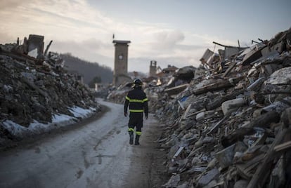 Un bombero camina por lo que un d&iacute;a fue la calle principal de Amatrice.