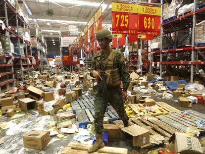 Soldado chileno monta guarda num supermercado afetado por saques, em 22 de outubro.