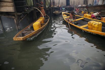 Varias personas recogen agua desde sus canoas en un punto de venta de la laguna de Lagos (Nigeria).