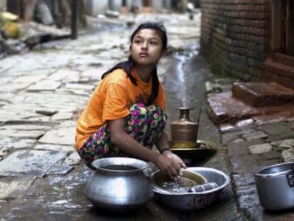 Una niña nepalí friega sus platos en Katmandú (Nepal).