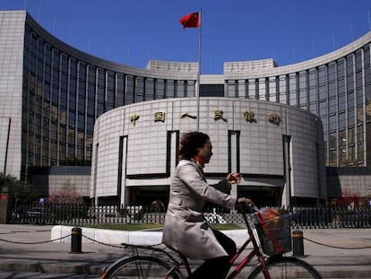 Una mujer en bicicleta pasa frente al Banco Popular de China.