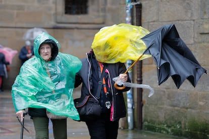 Turistas sufren las consecuencias del fuerte viento hoy en la plaza del Obradoiro en Santiago de Compostela.