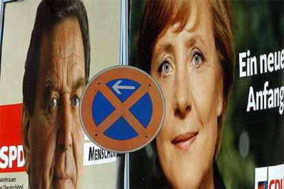 Los carteles electorales de Schröder y Merkel aparecen tras una señal de tráfico en la ciudad de Dresde.