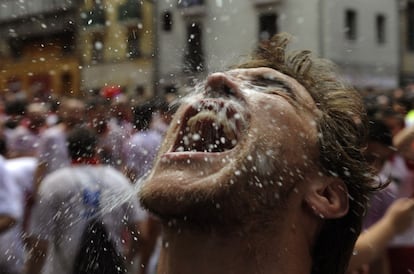 Un joven se empapa con agua tras el "Chupinazo", anunciando el inicio de las fiestas.