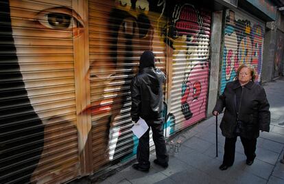 Uno de los artistas que ayer participó en la iniciativa de arte urbano 'Persianas Libres' da los últimos retoques a su grafiti.