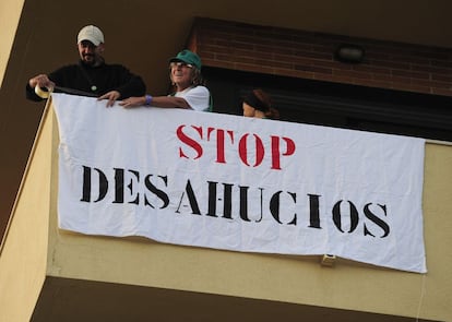 Activistas de PAH cuelgan una pancarta en uno de los balcones del edificio.