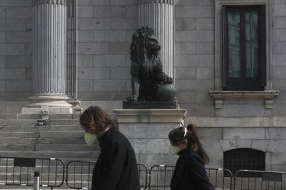 Dos transeúntes caminan frente al Congreso de los Diputados en Madrid.