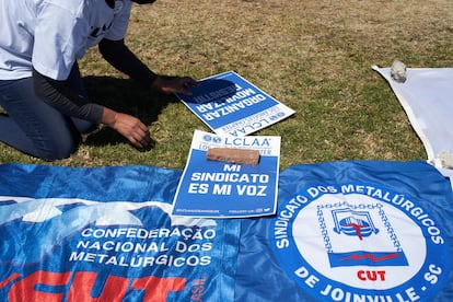 Una miembro del grupo de defensa del Consejo Laboral para el Avance Latinoamericano coloca carteles afuera del complejo Silao de General Motors, el miércoles 2 de febrero de 2022.