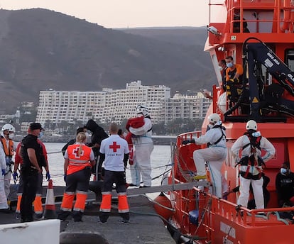 Miembros de la Cruz Roja ayudan a bajar del barco a migrantes en el puerto de Arguineguín (Gran Canaria, España) a 17 de marzo de 2021. 79 inmigrantes de origen subsahariano que viajaban a bordo de dos pateras fueron trasladados esa tarde noche por Salvamento Marítimo hasta el muelle de Arguineguín, en el Sur de Gran Canaria, después de rescatarlos en alta mar. Entre ellos viajaban varios bebés, mujeres jóvenes y adultos.
