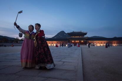 Dos mujeres con vestidos tradicionales hanbok posan para una autofoto ante el palacio de Gyeongbokgung en Seúl.