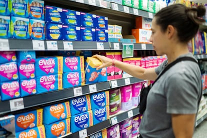 Una mujer compra compresas en un supermercado.