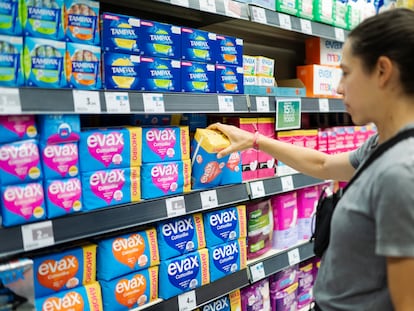 Una mujer compra compresas en un supermercado.