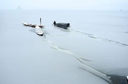 Un barquero usa un remo para romper la capa de hielo de la porción congelada del lago Dal después de una fuerte nevada en Srinagar (India).