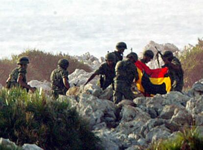 Un grupo legionarios recoge una bandera española antes de abandonar Perejil.