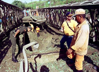 Varios policías examinan los desperfectos en un puente de Molino Viejo, a 70 kilómetros de Medellín, que el ELN voló ayer con dinamita.
