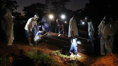 Um homem chora junto ao caixão de seu pai, morto em decorrência do coronavírus, no cemitério da Vila Formosa em São Paulo.