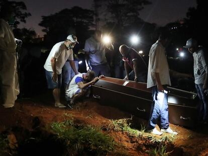 Um homem chora junto ao caixão de seu pai, morto em decorrência do coronavírus, no cemitério da Vila Formosa em São Paulo.