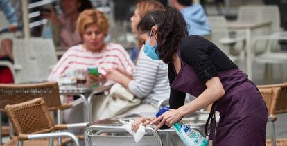Una trabajadora desinfecta las mesas y sillas de una terraza en la Plaza del Castillo de Pamplona.
