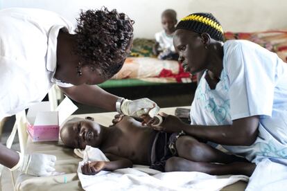 Una enfermera y una madre miman a uno de los pequeños pacientes. Ha tenido diarreas fuertes y su salud está muy deteriorada. Además, padece malaria.