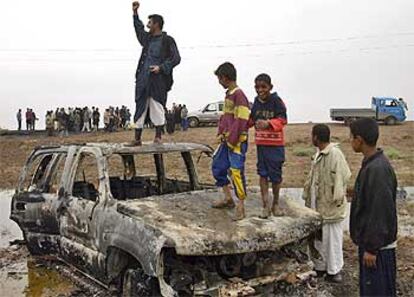 Varios iraquíes se exhiben sobre un coche de los agentes españoles del CNI muertos en un atentado.