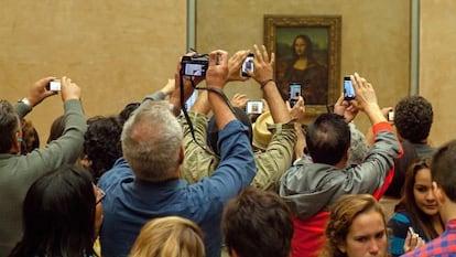 Decenas de turistas fotografían la Mona Lisa en el Louvre.