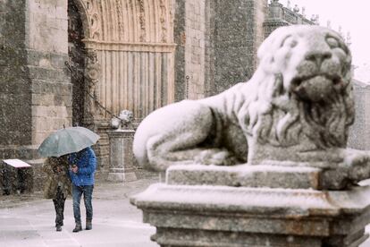 Dos personas se protegen este miércoles de la nieve junto a los leones de la catedral de Ávila. Aunque estas imágenes blancas puedan chocar a estas alturas de la primavera, “la nieve no es desconocida por estas fechas en las principales cordilleras españolas” ni tampoco en dichas capitales, donde nieva “dos días en promedio cada mes de abril”, según el portavoz de la Agencia Estatal de Meteorología, Rubén del Campo.