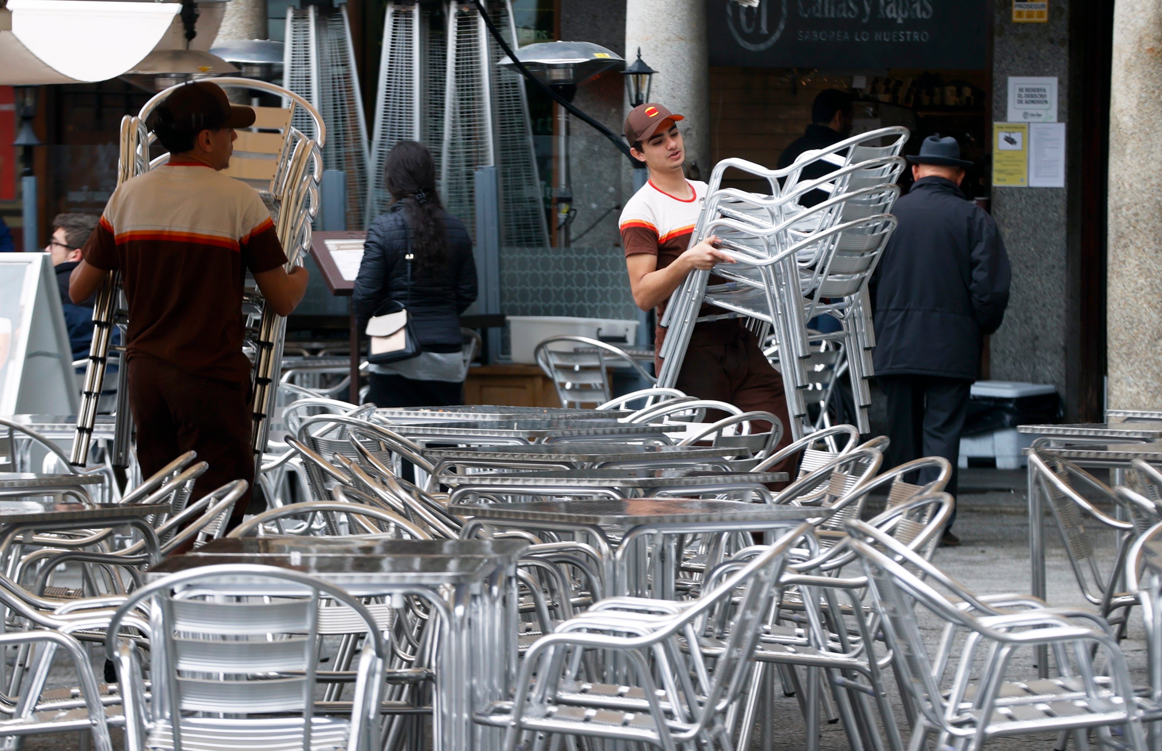 Varios trabajadores preparan las mesas de una terraza en un bar de Toledo.