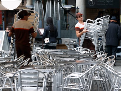 Varios trabajadores preparan las mesas de una terraza en un bar de Toledo.