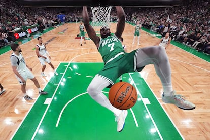 Boston Celtics guard Jaylen Brown hangs on the rim after a dunk during the first half against the Dallas Mavericks in Game 5 of the NBA basketball finals Monday, June 17, 2024, in Boston.