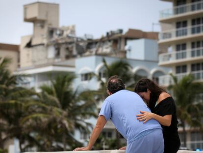 Una pareja frente al edificio parcialmente derrumbado en Surfside, Miami.