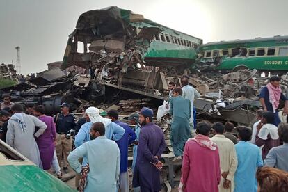 Un grupo de personas se reúnen alrededor de los restos de los vagones de los dos trenes que han chocado en el distrito de Rahim Yar Khan (Pakistán). Al menos 10 personas murieron y 40 resultaron heridas tras la colisión.