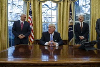Trump, flanqueado a la izquierda por el vicepresidente, Mike Pence, y a la derecha por su asesor en comercio, Peter Navarro, el lunes, el primer día laboral completo en que ha presidido EE UU.