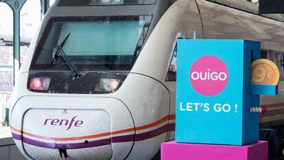Un tren de Renfe pasa junto a un cartel publicitario de Ouigo en la inauguración del nuevo trayecto Madrid-Segovia-Valladolid