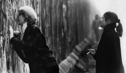 Uma mulher, que está do lado ocidental, olha através do muro de Berlim.