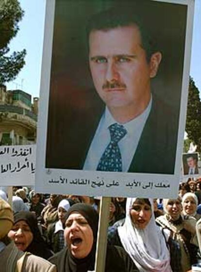 Unas mujeres portan pancartas con la foto de Bachar al Asad, en una protesta en Damasco contra la guerra en Irak.
