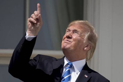 Trump señala al sol mientras lo observa sin gafas.