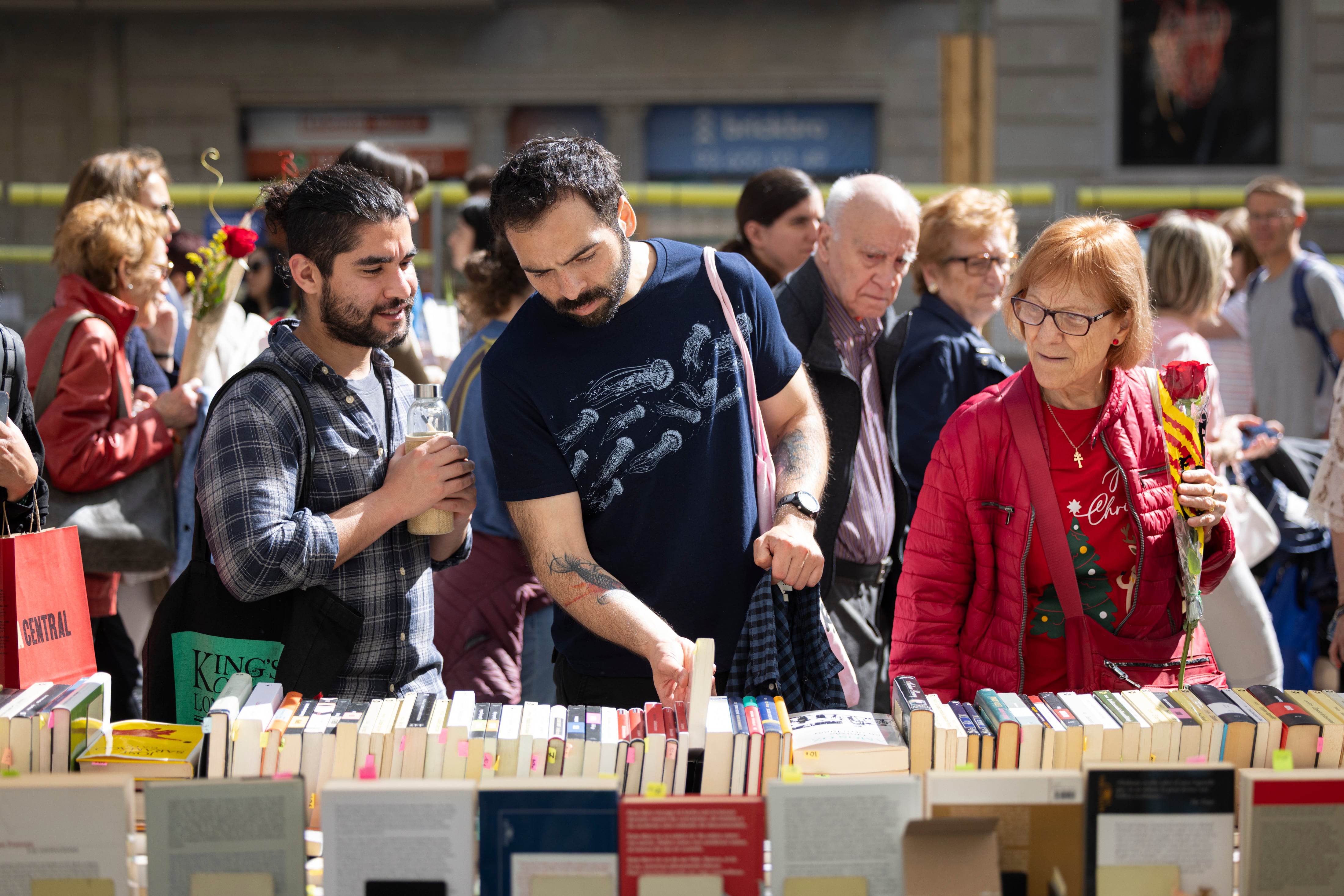 Varios paseantes miran libros en las Ramblas de Barcelona, este miércoles durante la Diada de Sant Jordi.