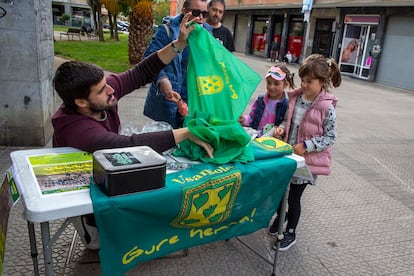 Un representante de Usansolo Herria regala a dos niñas unos pañuelos de esta agrupación vecinal.