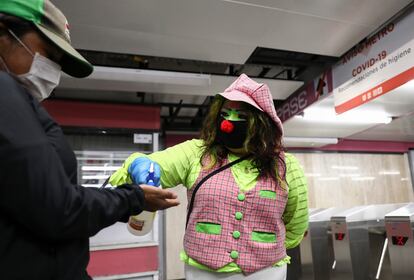 Una mujer vestida de payaso y con máscara facilita a los pasajeros gel en el metro de Ciudad de México.