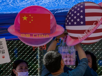 A vendor sets up foods and beverages at a booth displaying China and American flags during a Spring Carnival in Beijing, on May 13, 2023.