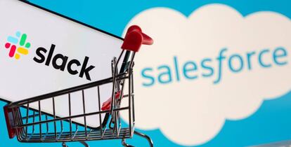 Smartphone with Slack logo stands in a shopping cart on a keyboard in front of displayed Salesforce logo in this picture illustration