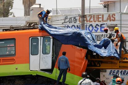 Trabajadores cubren uno de los vagones siniestrados horas después del derrumbe.