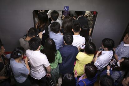 Usuarios del metro de Pekín (China) se agolpan en el andén de una estación intentando entrar en un vagón abarrotado de gente.