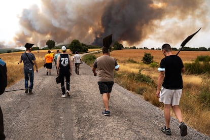 Varios jóvenes de las comarcas de Alba y Aliste cargan con los batefuegos para luchar contra las llamas, este martes en Losacio (Zamora). 