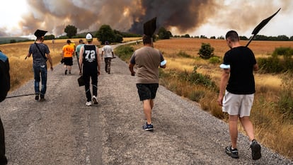 Varios jóvenes de las comarcas de Alba y Aliste cargan con los batefuegos para luchar contra las llamas, este martes en Losacio (Zamora).