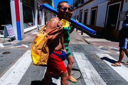 Una pareja camina hacia la playa por las calles de Chipiona (Cádiz).