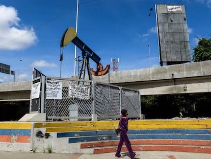 Una mujer camina en una plaza con una bomba de aceite en Caracas.